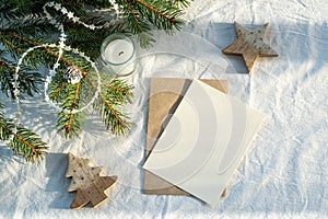 Blank greeting card, invitation card mockup.Christmas decoration scene in sunlight with card and envelope, ribbon, fir branches,