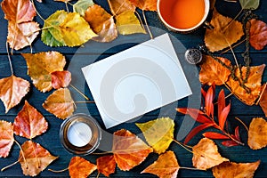 A blank greeting card or invitation with a cup of a tea, autumn leaves and a candle, an autumn stationery mockup