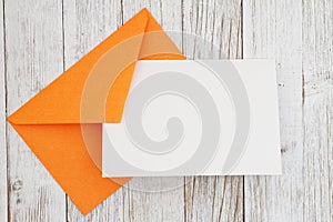 Blank greeting card with orange envelope on wood