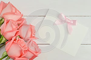 Blank greeting card with pink ribbon bow and pink rose flowers