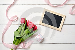 Blank greeting card with red tulips flowers on white wooden table. Romantic wedding card, greeting card for womans or mothers day,