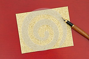 Blank greeting card on red wood with a fountain pen