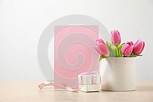 Blank greeting card, tulips and gift on table. Happy Mother`s day