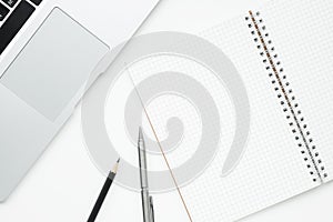 Blank grid lines notebook is on top of white office desk table. Top view, flat lay