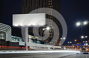 Blank illuminated billboard near well-lit road at night time. 3d rendering