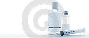 Blank label sanitizing gel bottle and medicine vial with a hypodermic syringe on a 16:9 banner