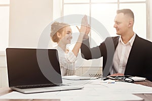 Blank laptop and happy man and woman doing high-five