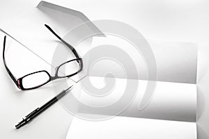 blank of letter paper and envelope with eyeglasses and pen