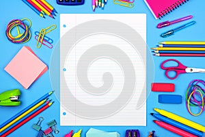 Blank lined paper with school supplies frame over a blue background