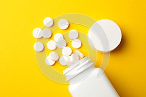 Blank medical bottle and pills on yellow background