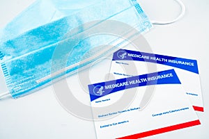 Blank Medicare health insurance cards and facial mask isolated on white