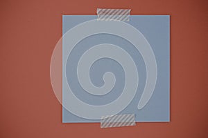 Blank memo square note on red background. Blank blue colored memo notes with ripped decorative adhesive washi tapes on