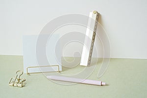 Blank memopad with gold metallic holder, ruler, pen, clip on desk. white ivory background. workspace office stationery photo