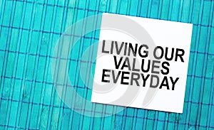 blank note pad with text living our values everyday on green wooden background