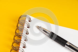 Blank note paper with pen on yellow background