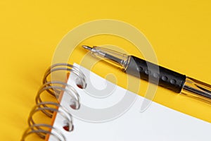 Blank note paper with pen on yellow background