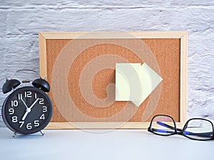 The blank note pinned on a cork board with clock and glasses