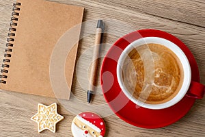 Blank notebook, black coffee cup, Christmas cookies and pen on wood table, Top view and copy space. Xmas, Happy New Year, Goals,