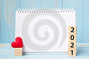 Blank notebook and 2021 cubes with red heart shape decoration on blue wooden table background. New Year NewYou, Goal, Resolution,