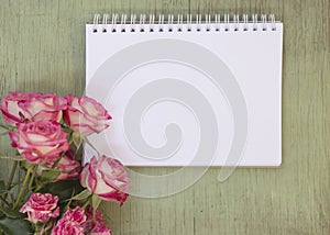 Blank notebook mock up for artwork with pink roses. Place for text. Fresh flowers on old wooden background.