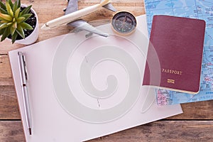 Blank notebook,passport,compass,airplane and map on wooden table