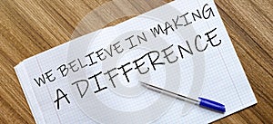 Blank notebook and pen. Isolated on white. whith text We Believe In Making A Difference