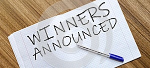 Blank notebook and pen. Isolated on white. whith text Winners Announced