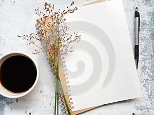 Blank notebook with pen next to a cup of coffee.