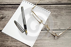 Blank notebook with pen are on top of white office desk table. Top view with copy space, flat lay
