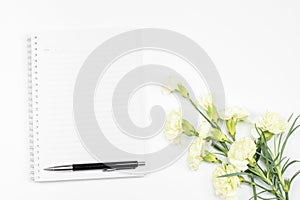 Blank notebook with pen and white carnation flower on white background