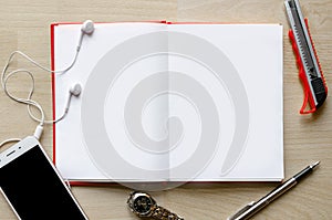 Blank notebook with pen on wood table And a wrist watch headset Modern phone Text input area