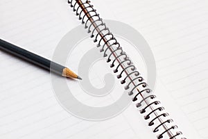 A blank notebook and a pencil in a close up view