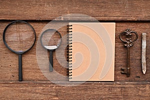 Blank notebook with pencil, key and magnifying glass