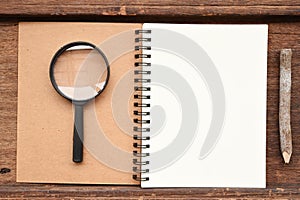 Blank notebook with pencil and magnifying glass