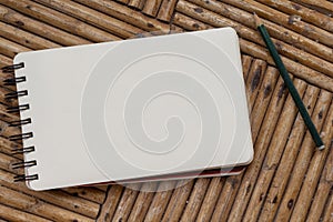 Blank notebook with pencil on rustic wooden table.Spiral notepad with white paper for message or drawing. photo