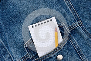 A blank notebook and pencil in workmans jeans pocket. photo