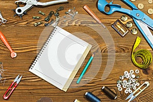 Blank notebook and Sewing tools on wooden textured background, copy-space.