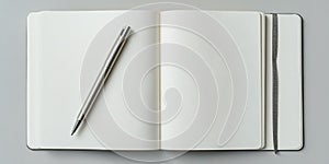 Blank notebook and silver pen on gray surface ready for writing ideas and notes