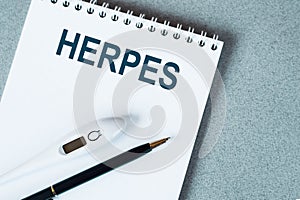 Blank notebook with thermometre and pen on table. HERPES word