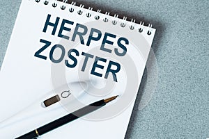 Blank notebook with thermometre and pen on table. HERPES ZOSTER text