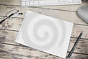 Blank notepad, glasses, pen and keyboard computer on a desk