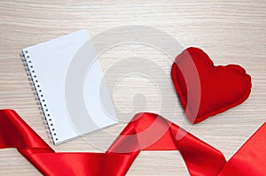 Blank notepad, heart and shaped ribbon on wooden table