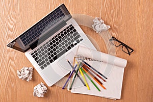 Blank notepad, laptop and pencils with sheets of crumpled paper