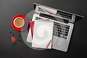 Blank notepad over laptop and coffee cup on office black table