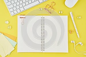 Blank notepad page in bullet journal on bright yellow office desktop. Top view of modern bright table with notebook, stationery.