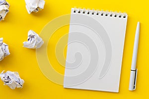 Blank notepad, pen and crumpled paper balls on bright yellow background. Writing message. Ð’rawing up a plan. New or bad idea
