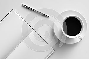 Blank notepad, pen and cup of coffee on a white table