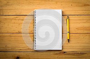 Blank notepad with pen or pencil on office wooden table in warm