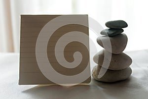Blank notepaper for your text with still life concept of the balancing white stones on the white background.