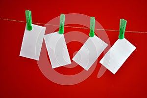 Blank notes hanging clipped on red background